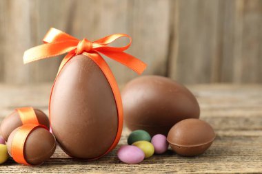 Mutlu Paskalyalar. Ahşap masada renkli şekerlemeli lezzetli çikolata yumurtaları, yakın plan. Metin için boşluk
