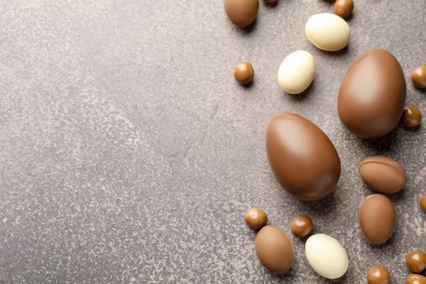 Paskalya kutlaması. Gri desenli masa üzerinde bir sürü çikolata yumurtası ve dragee, metin için boşluk ile düz yatıyordu.