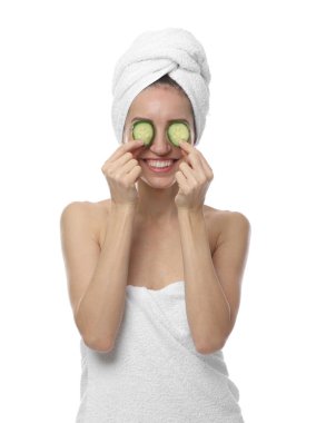 Havluya sarılı güzel bir kadın ve beyaz arka planda salatalık dilimleri.