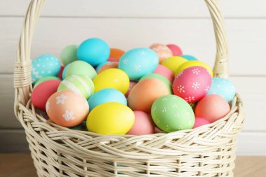 Güzel dekore edilmiş Paskalya yumurtaları hasır sepetin içinde masada, yakın plan.