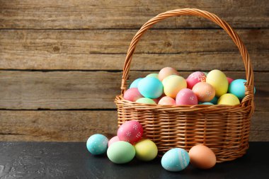 Güzel dekore edilmiş Paskalya yumurtaları hasır sepetin içinde siyah masada, metin için yer var.
