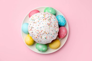 Nefis dekore edilmiş Paskalya pastası ve pembe arka planda yumurtalar, üst manzara.