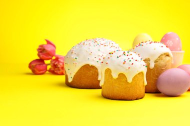 Lezzetli Paskalya pastaları, sarı arka planda yumurtalar ve laleler