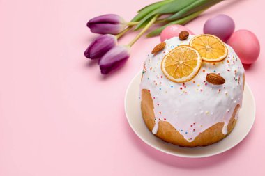 Güzel Paskalya pastası, pembe arka planda yumurtalar ve laleler, yakın plan. Metin için boşluk