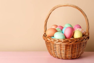 Güzel Paskalya yumurtaları pembe ahşap masada, bej arka planda. Metin için boşluk
