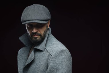 Moda modeli. Siyah arka planda şık giyinmiş yakışıklı bir adam, metin için yer var.