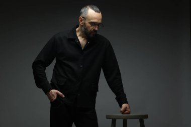 Moda modeli. Gri arka planda dışkısı olan yakışıklı bir adam.