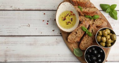 Ekmek, zeytin, baharatlı yağ ve ahşap masa üzerinde fesleğen, üst manzara. Metin için boşluk