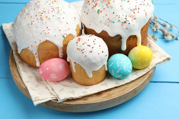 Lezzetli Paskalya pastaları, yumurtalar ve söğütler mavi ahşap masada, yakın plan