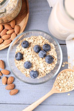 Yulaf gevreği, fındık, badem sütü ve yaban mersini gri ahşap masa, düz uzanmış