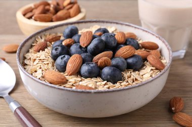 Yulaf gevreği, badem sütü, böğürtlen ve fındık, ahşap masa, yakın plan.