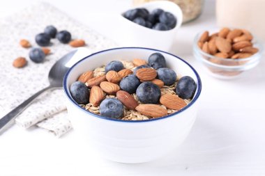 Yabanmersinli yulaf ezmesi ve beyaz ahşap masada fındık, yakın plan.