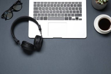 Kulaklıklar, kahve, bardaklar, dizüstü bilgisayar ve siyah arka planda çiçek dekoru, düz yatak. Metin için boşluk