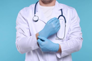 Doktor açık mavi arka plana eldiven takıyor, yakın plan.