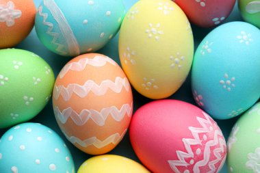 Many painted Easter eggs on light blue background, flat lay