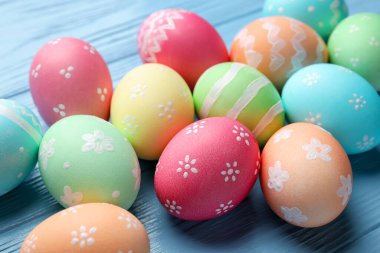 Güzel dekore edilmiş Paskalya yumurtaları açık mavi ahşap masada, yakın plan.