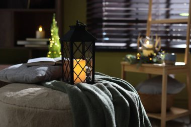 Kapalı alanda yanan mum ve battaniyeli Noel feneri. Bokeh etkisi