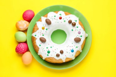 Lezzetli Paskalya pastası ve sarı arka planda boyanmış yumurtalar.