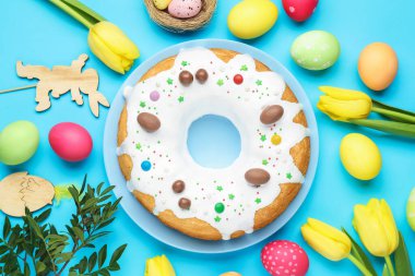 Lezzetli Paskalya pastası, boyanmış yumurtalar, güzel laleler ve açık mavi arka planda diğer dekorlar, düz uzanış