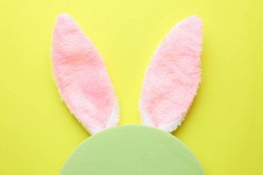 Mutlu Paskalyalar. Tavşan kulaklı şirin saç bandı ve açık yeşil arka planda boş podyum, üst manzara.