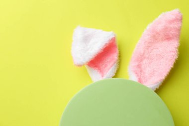 Mutlu Paskalyalar. Tavşan kulaklı şirin saç bandı ve açık yeşil arka planda boş podyum, üst manzara. Metin için boşluk