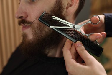 Berber dükkanında adamın sakalını buduyor, yakın plan.