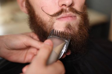 Berber dükkanında adamın sakalını buduyor, yakın plan.