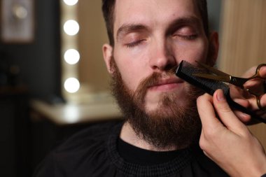 Berber dükkanında adamın bıyığını buduyor, yakın plan. Metin için boşluk