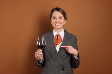 Kahverengi arka planda kırmızı şarap kadehi olan profesyonel şarap garsonu.