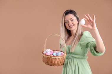 Paskalya kutlaması. Bej arka planda Hasır sepeti dolu gülümseyen kadın, mesaj için yer