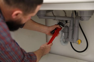 Boru anahtarını tamir eden tesisatçı. Kapalı alanda, kapalı.