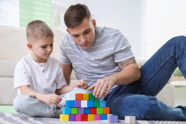 Baba ve oğlu evlerinde bloklarla oynuyorlar.