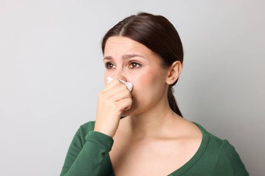 Hafif arka planda burnu akan bir kadın. Soğuk Semptom