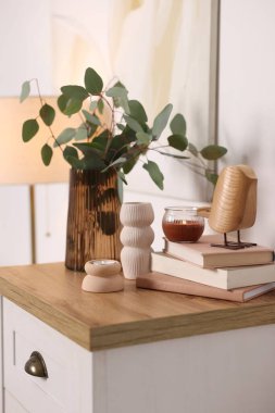 Beyaz duvarın yanındaki dolapta güzel vazolar ve diğer dekorlar var.