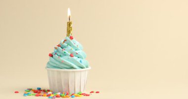 Üzerine şeker serpiştirilmiş kek ve bej arka planda yanan mum. Metin için boşluk