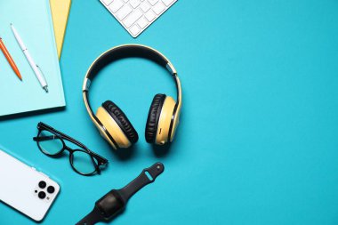 Açık mavi arkaplan üzerinde kulaklık ve kırtasiye ile düz kompozisyon, metin için boşluk