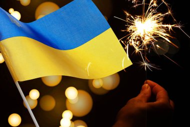 Ulusal bayrak taşıyan Ukrayna bayramı tebrik kartı tasarımı. Siyah arkaplanda yanan maytap ve bokeh ışıkları