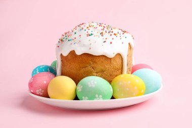 Nefis dekore edilmiş Paskalya pastası ve pembe arka planda yumurtalar.