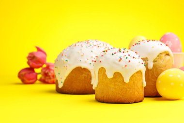 Lezzetli Paskalya pastaları, sarı arka planda yumurtalar ve laleler