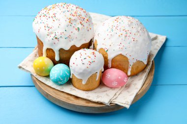 Lezzetli paskalya pastaları ve yumurtalar mavi ahşap masada, yakın plan.