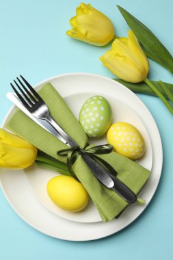 Paskalya kutlaması. Lale çiçekleri ve açık mavi arkaplan üzerine boyanmış yumurtalar ile şenlik masa ayarı, düz yatıyordu