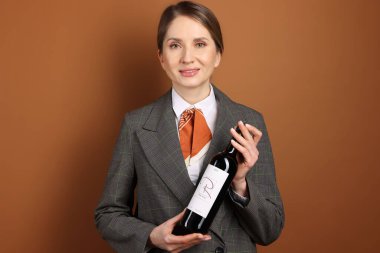 Kahverengi arka planda şarap şişesi olan profesyonel şarap garsonu.