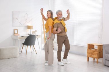 Mutlu yaşlı çift evde dans ediyor.