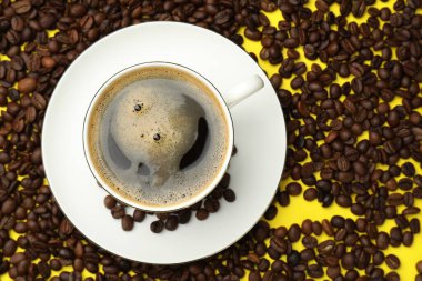 Kahveyi fincanda tazelemek ve sarı arka planda fasulye, düz uzanmak.