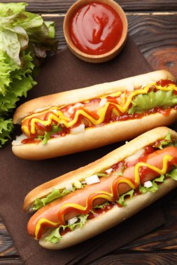 Ahşap masada soslu ve marullu lezzetli sosisliler.