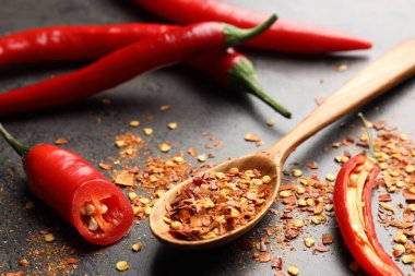 Kırmızı biber ve tanecikler gri masada, yakın plan.