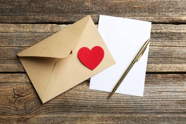 Zarfta aşk mektubu, kırmızı kalp ve tahta masa üzerinde kalem, düz yatıyordu.