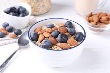 Yulaf gevreği, yaban mersini, fındık ve badem sütü, beyaz ahşap masada, yakın plan.