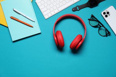 Açık mavi arkaplan üzerinde kulaklık ve kırtasiye ile düz kompozisyon, metin için boşluk