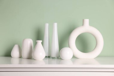 İçerideki soluk yeşil duvarın yanında güzel vazolar var.